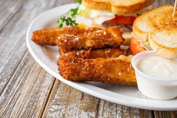 A view of a portion of deep fried zucchini sticks, part of a prepared entree, in a restaurant or kitchen setting.