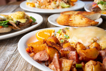 A view of several prepared entrees on a table, featuring a plate of potatoes and an omelet, in a restaurant or kitchen setting.