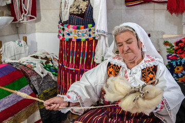 An old woman weaver spun wool on her hand