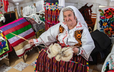 An old woman weaver spun wool on her hand