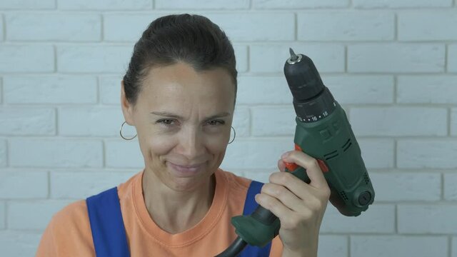 Woman with drill. A tricky woman hold a working drill in her hand on her working place.