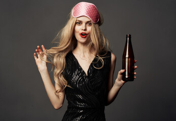 Beautiful blonde with a pink sleep mask and a bottle of beer in her hand