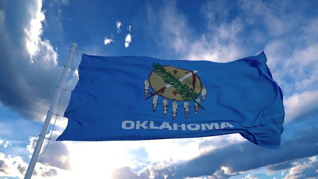 Oklahoma flag on a flagpole waving in the wind, blue sky background. 4K