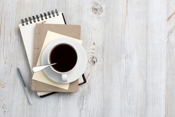 desk office with blank notepad, coffee cup and pen on wood table. Flat lay top view copy space.
