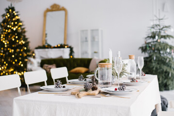 Beautiful served table with decorationsand lanterns. Living room decorated with lights and Christmas tree. Holiday setting