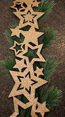 golden star border or garland on fir or pine branches with warm grey granite plate background