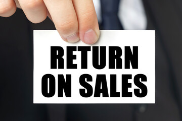Businessman shows a card with the text RETURN ON SALES