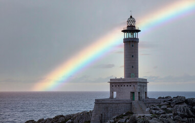 punta nariga lighthouse on the coast with the rainbow