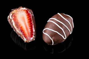 Chocolate truffle with strawberry filling isolated on black background. Closeup photography.