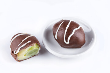 Chocolate truffle with green grape filling isolated on white background. Closeup photography.
