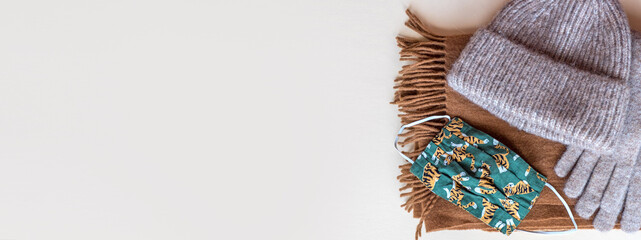 Banner of warm Winter cloths and a Covid face mask