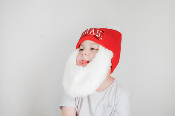 toddler boy in Santa Claus costume with beard and red hat on white background