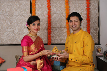 Fototapeta na wymiar Indian couple with sweets and gifts while celebrating Diwali, Deepavali or Dipavali festival.