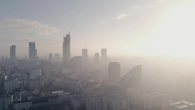 Top view on downtown of big city with foggy weather and sun lights. Skyscraper top view with crane on great height. City view from drone.