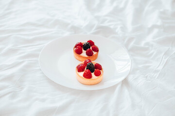 Raspberry tartlets with cheese creme, fresh berries on white plate. Fresh fruit tart on white background