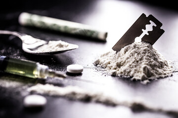 cocaine with rows, rows and lines of powder to be tested, with a drool blade beside it and syringes