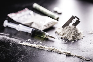 cocaine with rows, rows and lines of powder to be tested, with a drool blade beside it and syringes