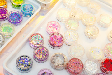 Palette of colorful shiny glitter in round plastic cans