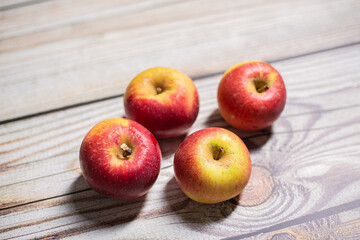 Four red and yellow autumn apples fruit on a wooden surface