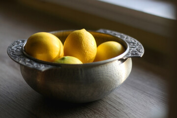 Fresh lemons in vintage silver bowl. Selective focus.