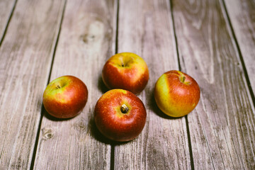 Four red and yellow autumn apples fruit on a wooden surface
