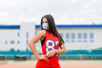 Portrait of tennis player girl holding a ball outside with protective masks