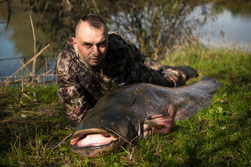 Naklejka premium Fisherman holding a giant catfish. Catch of fish, freshwater fishing, monster fish