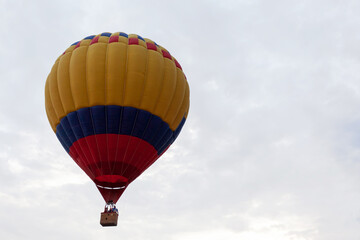 Striped yellow blue red balloon against cloudy sky