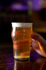 hand holding a glass of beer in a dark background 