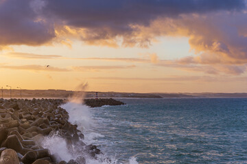Peniche lighthouse with Supertubos beach on the background at sunset with waves crashing, in Portugal
