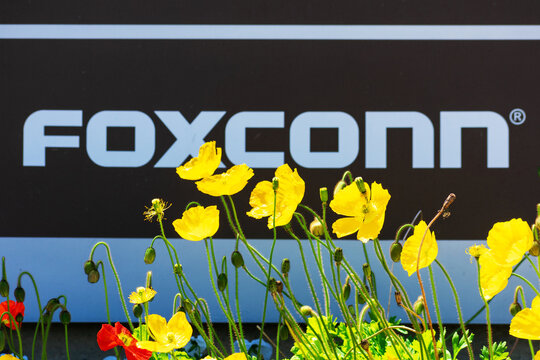 Blurred Foxconn sign in a blooming landscape. Hon Hai Precision Industry Co., Ltd., trading as Foxconn Technology Group, is a Taiwanese electronics contract manufacturer - Santa Clara, CA, USA - 2020