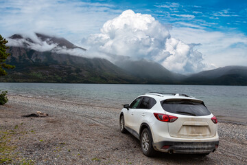 Fototapeta na wymiar British Columbia, Canada. White Car riding on the offroad to a Lake during cloudy summer day.