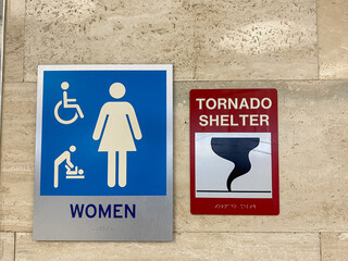 The women's restroom and tornado shelter signs directing people to the shelter