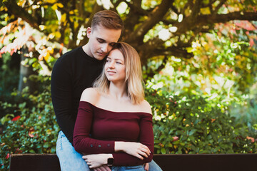 Young caucasian couple in love enjoys a moment of happiness in nature. The young man hugs his girlfriend on a romantic date in the fall park. Autumn mood. Selective focus. Copy space.