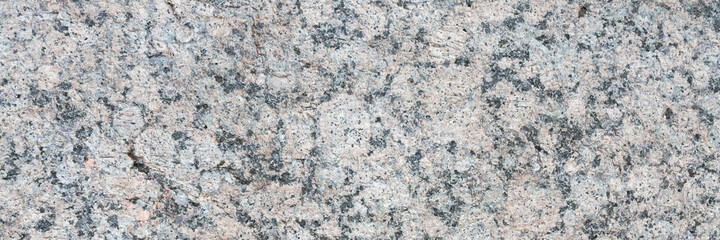 Granite texture. Natural granite with a grainy pattern. Stone background. Solid rough surface of rock. Durable construction and decoration material. Close-up.