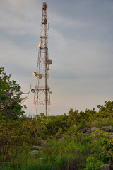 This unique photo shows a transmitter and telephone pole in Thailand standing on top of a mountain in the middle of nature at sunset