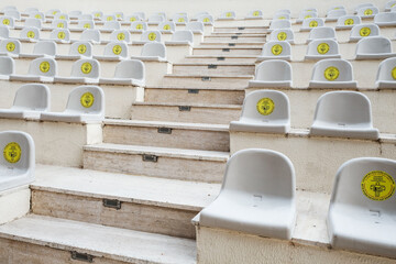 Rows of seats in amphitheater with warning sign for for social distancing during coronavirus outbreak. New normal lifestyle in world pandemic. Keeping safe distance between guests for performance.