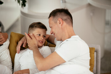Father and son enjoying in bed. Happy man with son relaxing in bed