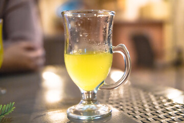 half glass of Orange yellow refreshing liquid in a restaurant or a bar at night 