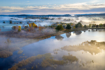 Naklejka na ściany i meble Beautiful aerial view of morning fog and sunrise in autumn forest.