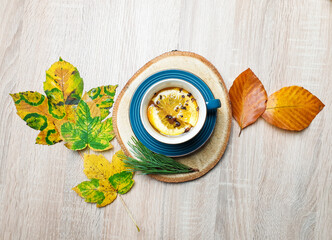 Autumn still life. Copy space mockup of an autumn composition with warm tea and maple leafs on a wooden background. Fall and Thanksgiving concept. Styled stock flat lay photo. Top view, vertical.