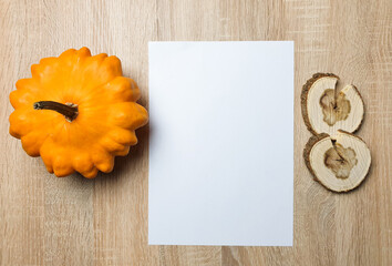Autumn still life. Blank copy space card mockup of an autumn composition with pumpkin and leafs on a wooden background. Fall and Thanksgiving concept. Styled stock flat lay photo. Top view, vertical.