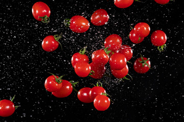 Freeze motion of flying cherry tomatoes, isolated on black background.