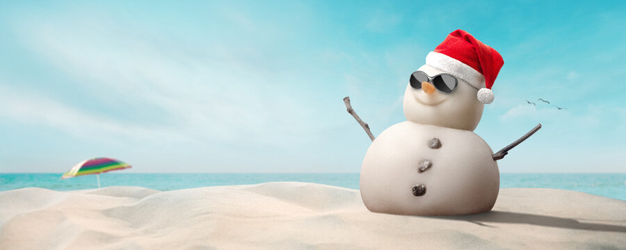 concept - happy sandy snowman with sunglasses and Santa hat on sunny Christmas day afternoon