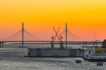 cable-stayed bridge over the river and floating dock at sunset