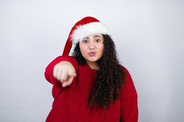 Young beautiful woman wearing a Santa hat over white background pointing to the front with finger