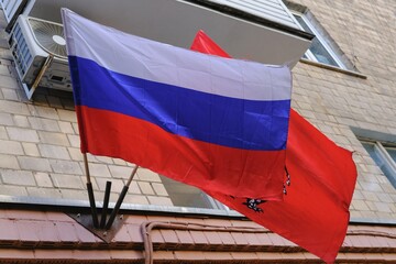 Russian tricolor flag and Moscow city flag on facade of residential building.Traditional urban patriotic street decoration before national holidays in Russia.