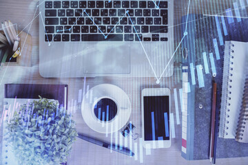 Double exposure of financial graph hologram over desktop with phone. Top view. Mobile trade platform concept.