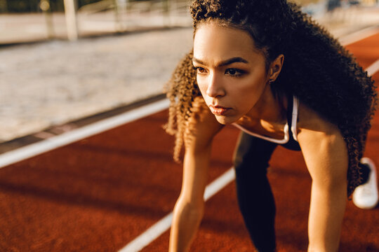Young athletic african american runner at stadium starting line getting ready for race, sport concept