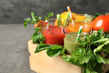 Delicious vegetable juices and fresh ingredients on grey table, closeup